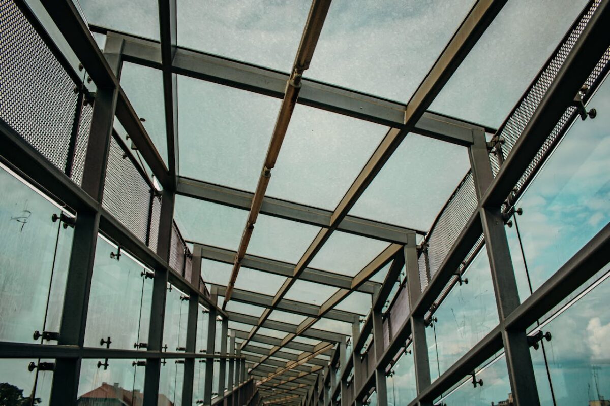 Abstract view of a modern glass and steel walkway with open sky view.