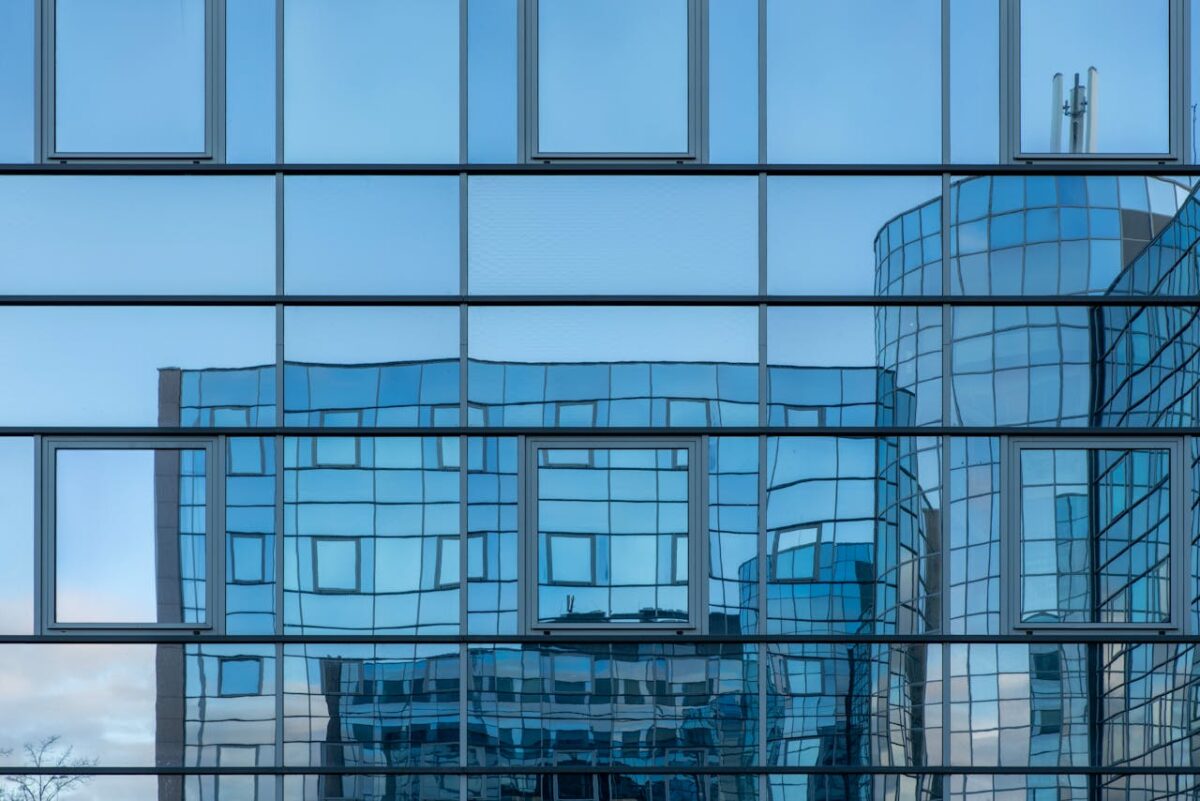 Close-up of a modern glass building facade reflecting another skyscraper.